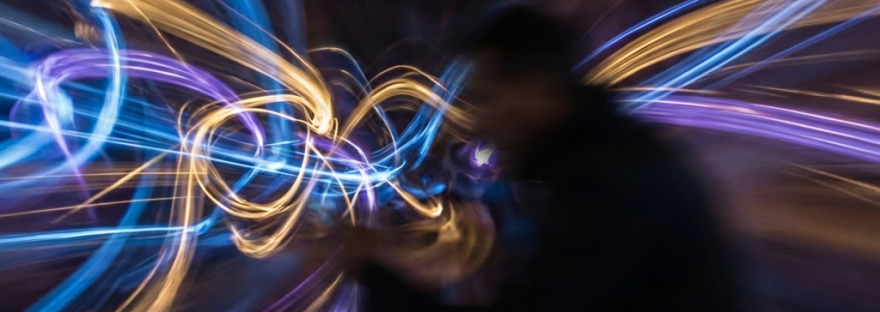 Swirling trails of blue, purple, and gold light against a dark, blurred backdrop.