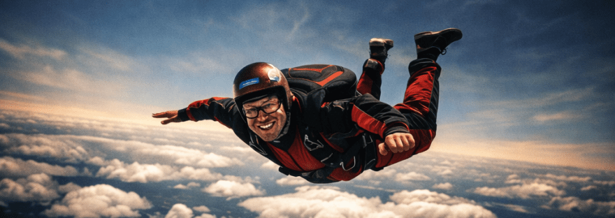 Skydiver in red and black jumpsuit freefalling from white airplane above clouds and farmland